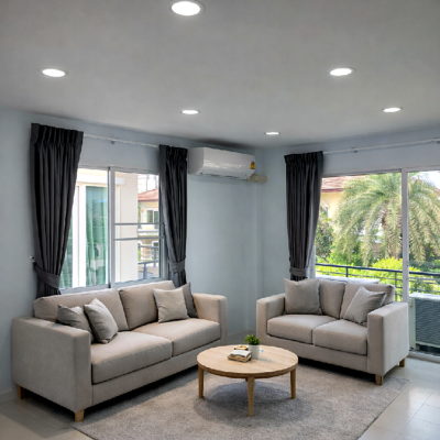 ห้องนั่งเล่นสไตล์มินิมอลที่มีโซฟาสีเทาอ่อนสองตัว โต๊ะกาแฟไม้ทรงกลม พรมสีเทา และแสงธรรมชาติจากประตูกระจกบานใหญ่พร้อมผ้าม่านสีเทาเข้ม