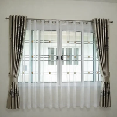 ผ้าม่านตาไก่ลายดอกไม้สีเบจเมทัลลิกติดตั้งคู่ผ้าโปร่งสีขาวตรงหน้าต่างกรอบเหล็กสไตล์โมเดิร์นพรีเมียม
